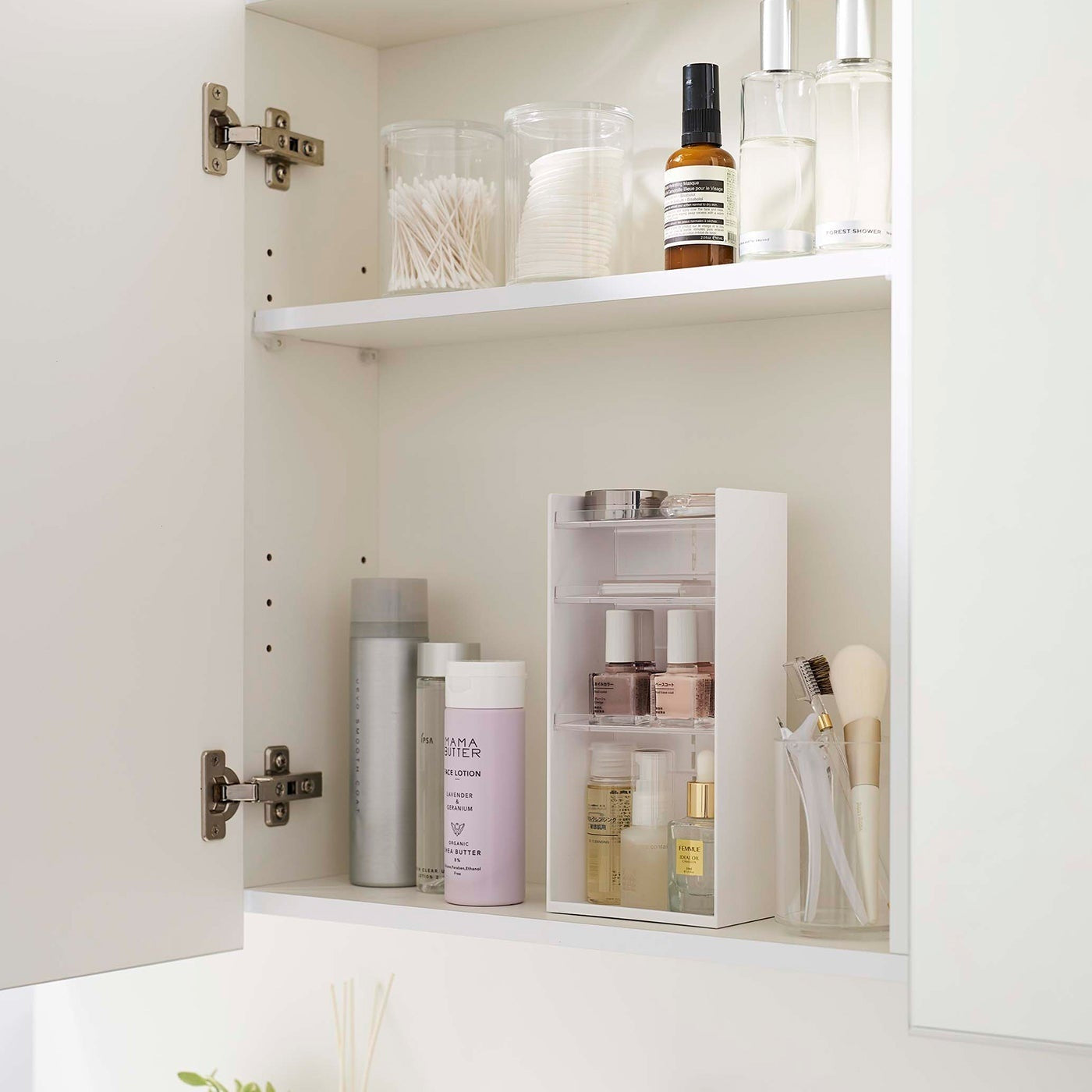 A white medicine cabinet is open to display the inside contents. Sunlight is focused on the right upper corner. Below is a bathroom sink.